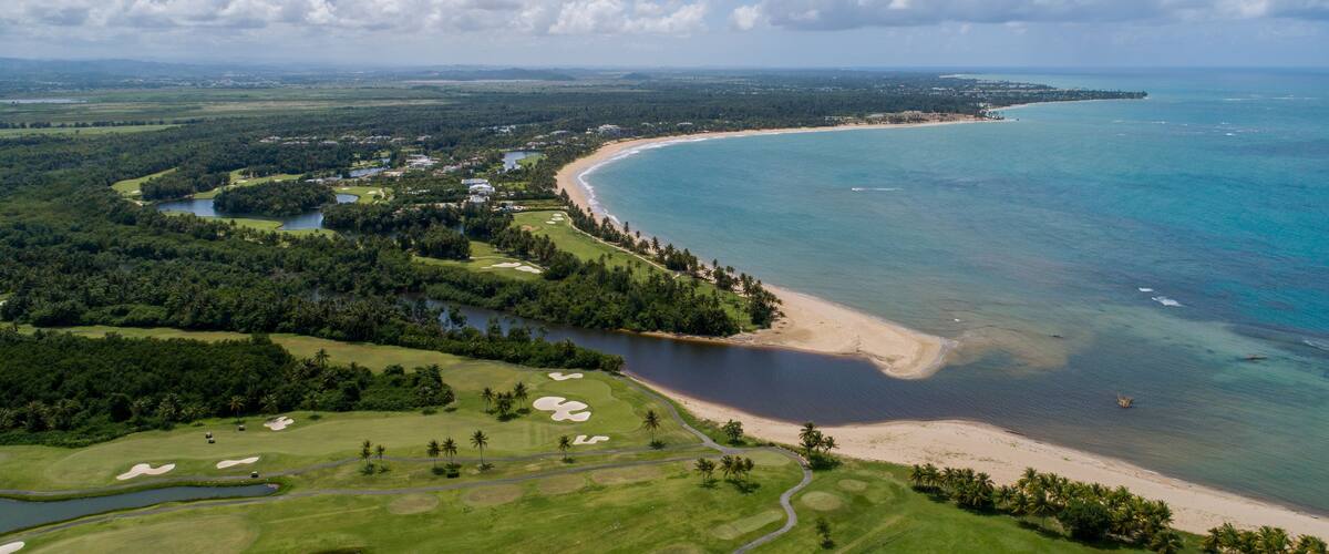 Eine Küstenlandschaft mit Golfplatz, Strand und einer Bucht.