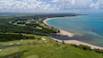 Un paysage côtier comprenant un terrain de golf, une plage et une baie.