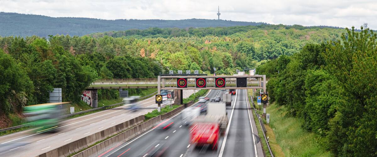 traffic on the autobahn with a speed limit of 80 kmh between the green forest