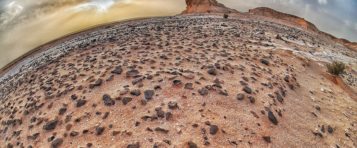 A desert landscape with a prominent rock formation and a clear sky.