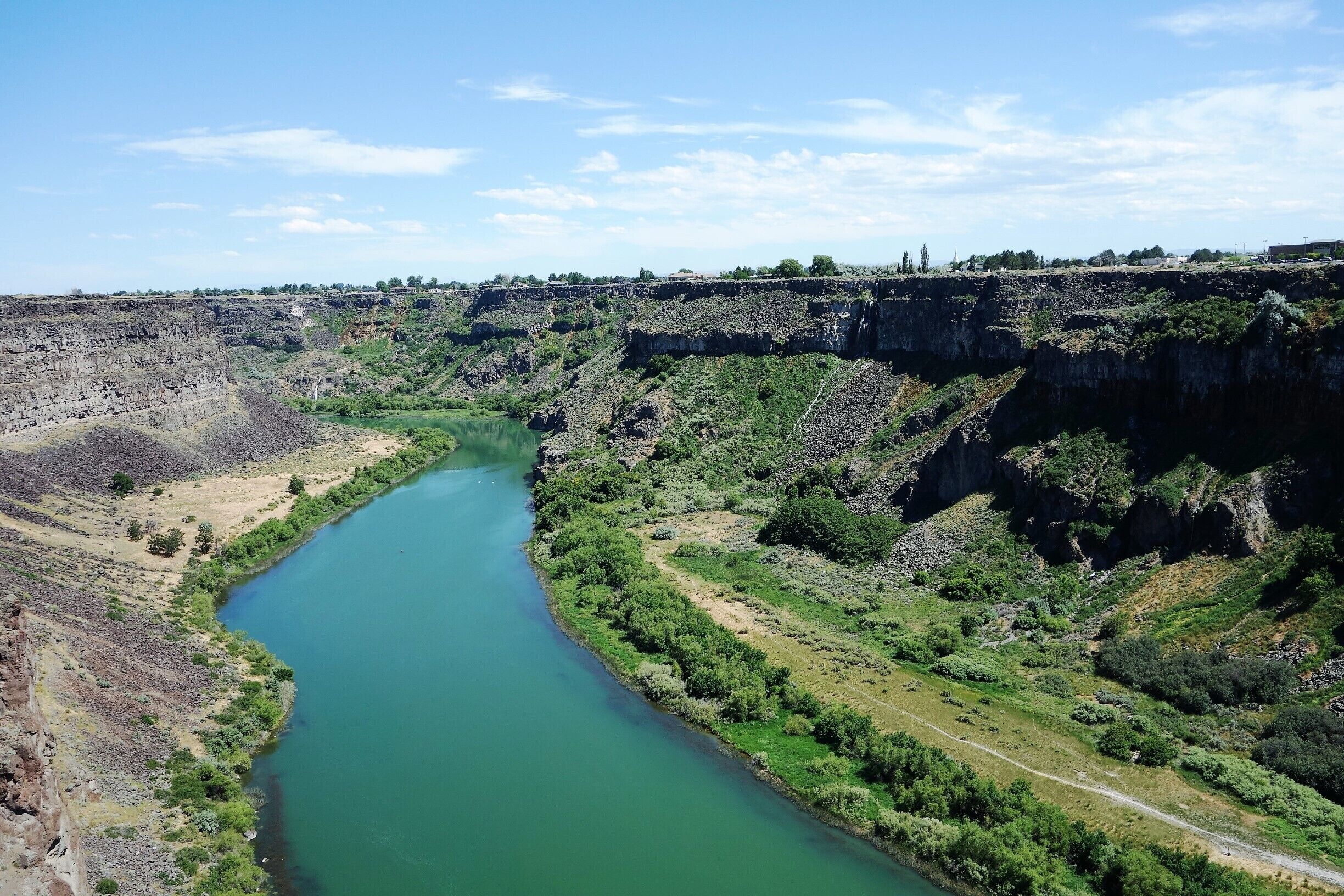 Een rivier kronkelt door een canyon met steile kliffen en schaarse begroeiing.