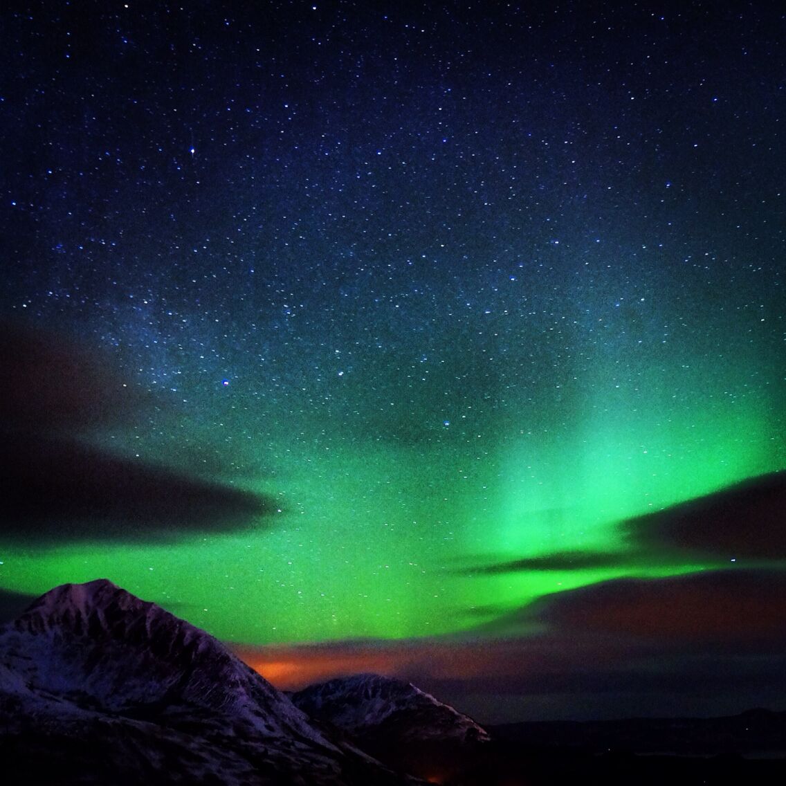 Three sisters basking in the green glow with Monashka Mountain lurking just behind while the village of Ouzinkie paints an orange hue beneath the northern lights. Oh yeah, and some stars.