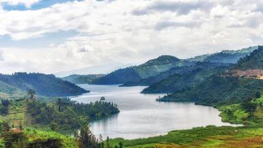 A river winding through lush green hills with a cloudy sky.