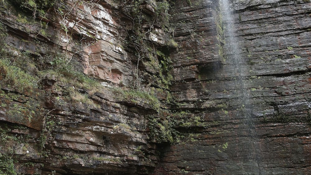 Dindefelo waterfall and tourist people, woman with child, kid. Kedougou, Senegal, Africa. Senegalese landmark, african scenic landscape, Kedougou scenery. Beautiful Dindefelo waterfall. Big waterfall