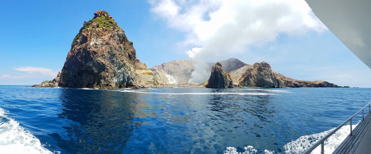 A rocky coastline with clear blue waters and a boat in the foreground.