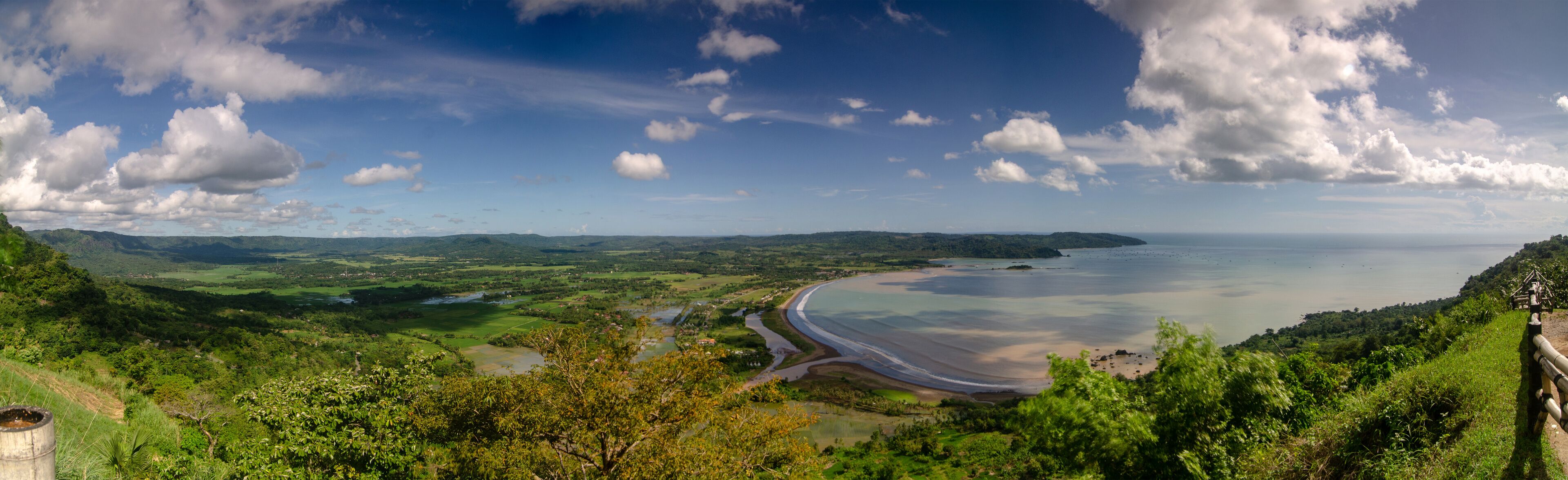 A coastal landscape with a beach, rolling hills, and a river.