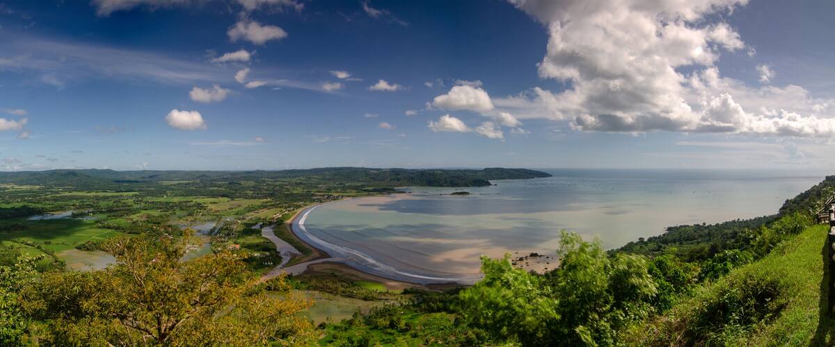 A coastal landscape with a beach, rolling hills, and a river.