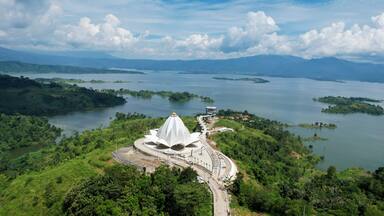 A white temple surrounded by lush greenery and a large body of water with islands.