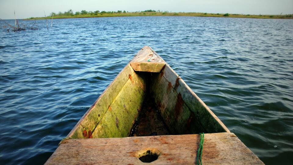 A wooden boat on a calm body of water with a distant shoreline.