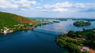 Aerial view of the Adomi Bridge stretching gracefully across the Volta River, a ribbon of steel connecting verdant shores under a vast sky, Atimpoku, Volta Region, Ghana.