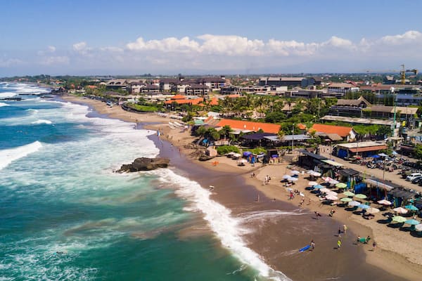 A coastal town with a beach, ocean waves, and buildings along the shore.