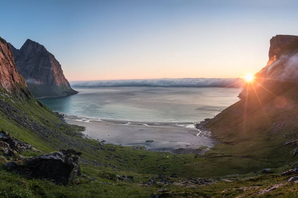 A coastal landscape with cliffs, a bay, and a sunset.