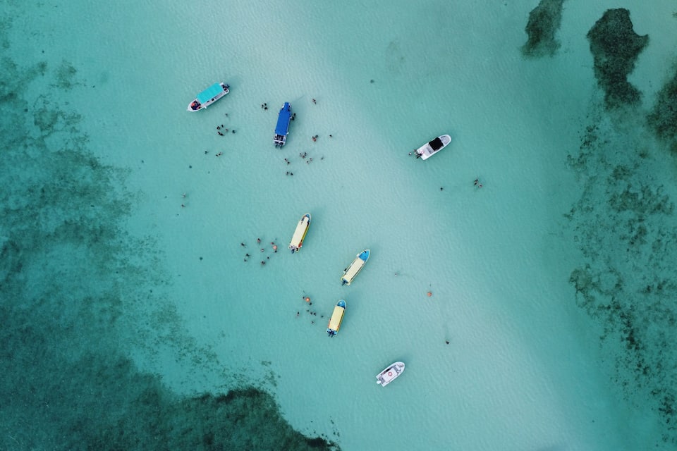 An aerial view of a turquoise sea with several boats anchored.
