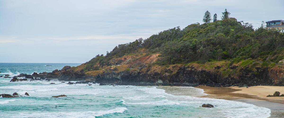Oxley Beach which includes a sandy beach, general coastal views and rocky coastline