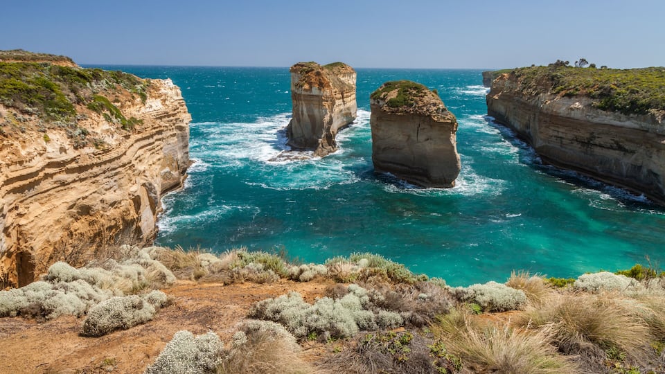 A coastal landscape with prominent rock formations and a clear blue sea.