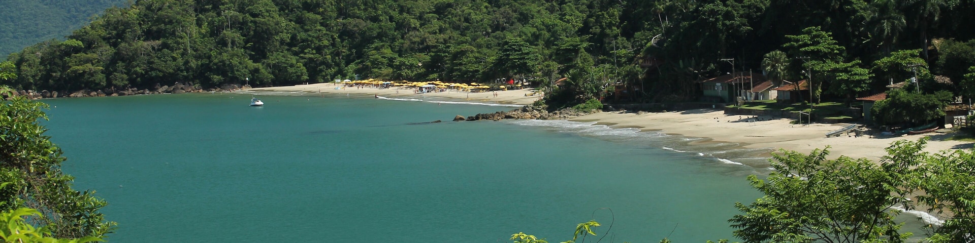 Vista panorâmica das praias da Almada e do Engenho em Ubatuba/SP, com mar tranquilo, montanhas cobertas de vegetação e céu ensolarado, destacando a beleza natural do litoral norte paulista