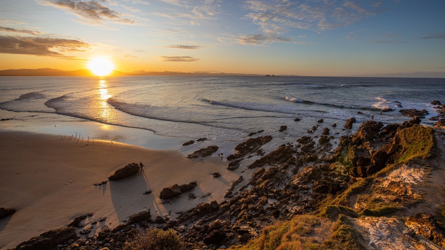 Little Wategos Beach showing rocky coastline, a sunset and a beach