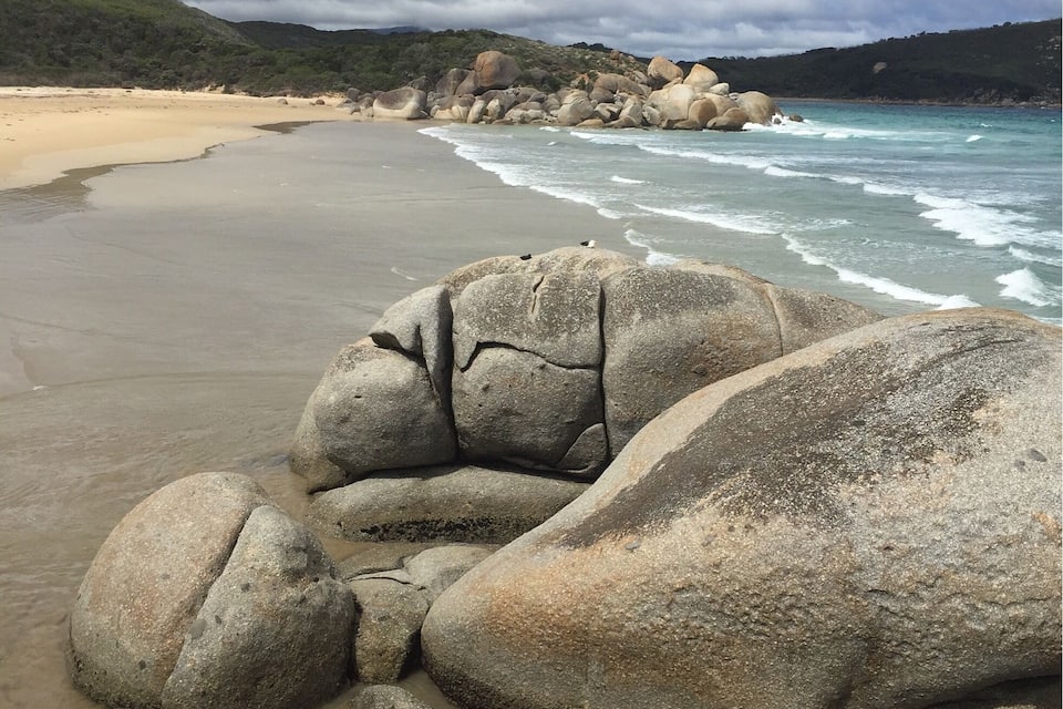 Una spiaggia con grandi massi e onde che si infrangono sulla riva.