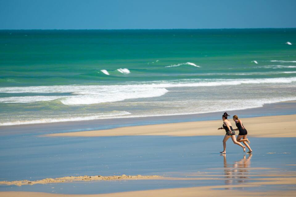 A beach with waves and two people running.