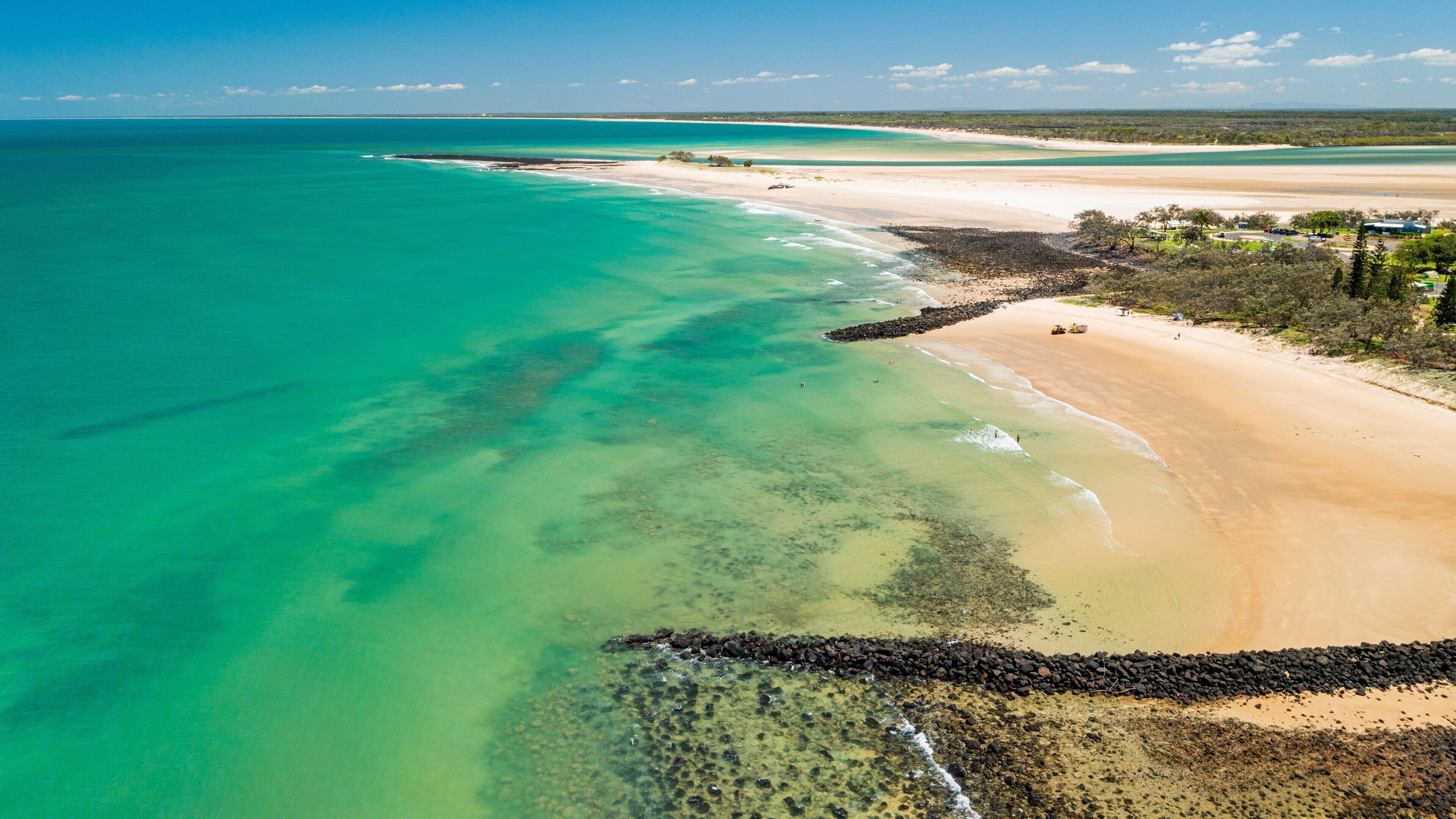 Un paysage côtier caractérisé par une eau turquoise cristalline, une plage de sable et une côte rocheuse.