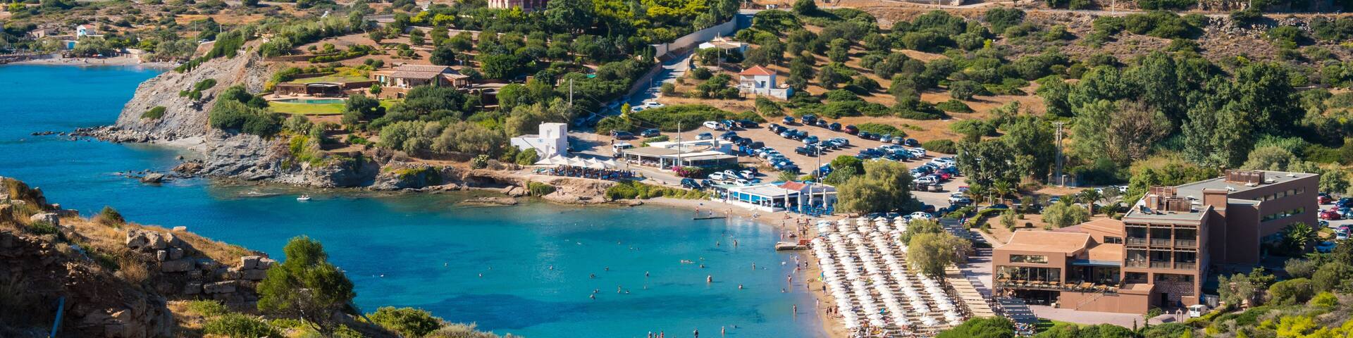 Un pueblo costero con casas en una colina, una playa y un mar azul cristalino.