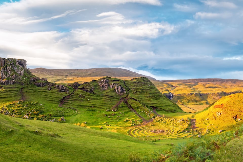 A mountainous landscape with a prominent rocky outcrop and terraced fields.