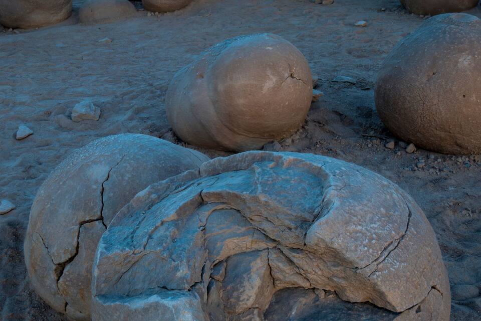 Grandes rocas esféricas en un paisaje desértico con una montaña al fondo.