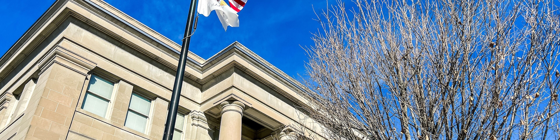 Exterior Views of the Appellate Court of the State of Illinois Fourth District Building in Springfield, Illinois, USA. American and State of Illinois Flags fly in the forefront of view.
