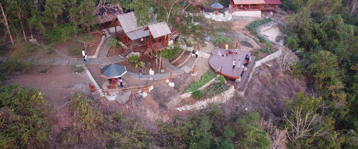 A forested area with wooden structures and a red-roofed building.