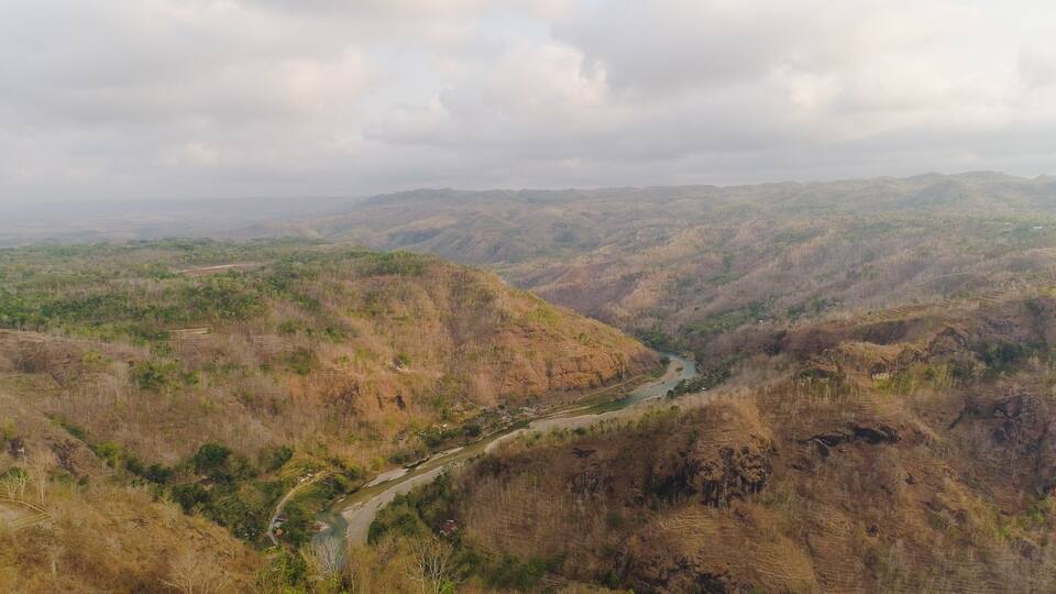 A river winding through a valley with terraced fields and distant hills.