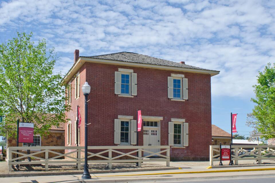A red brick building with white shutters and a flagpole with a flag.