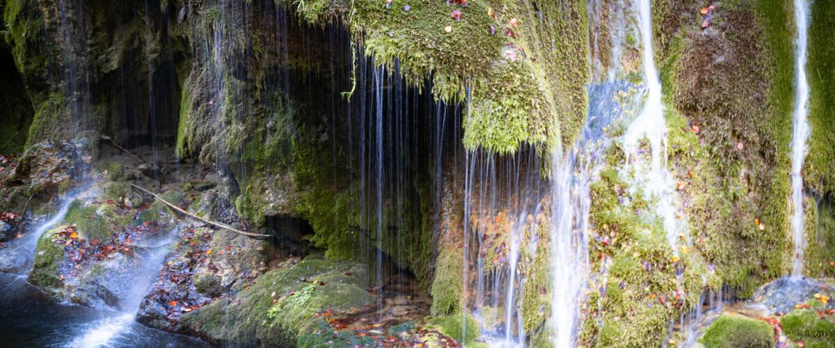 A moss-covered waterfall with multiple streams flowing over rocks.