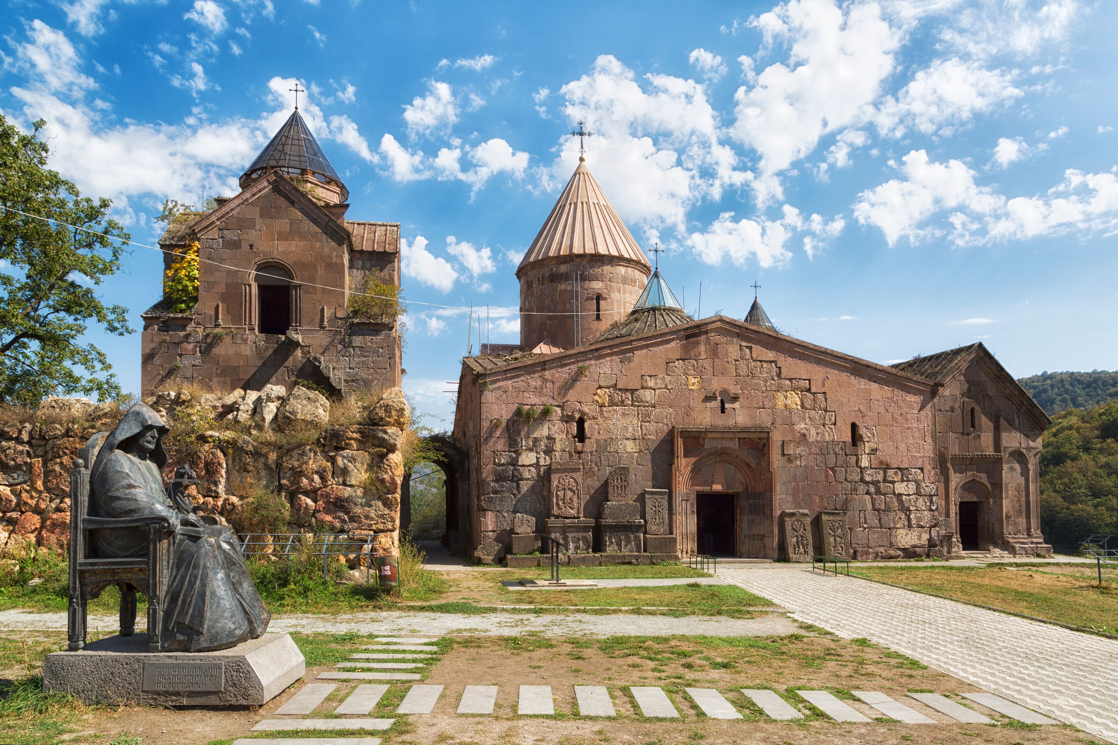 A historic church with a bell tower and a statue of a seated figure.
