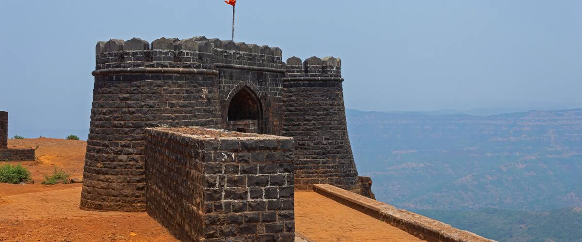 A stone structure with a flag on top, surrounded by a hilly landscape.