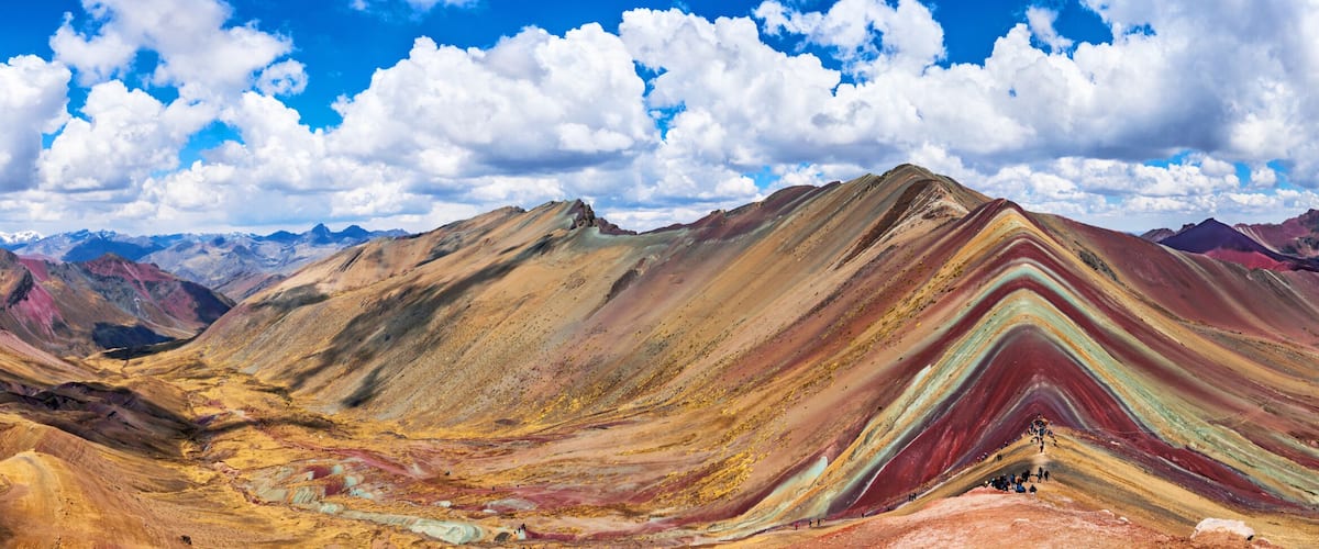 A mountain range with a striking multicolored striation pattern.