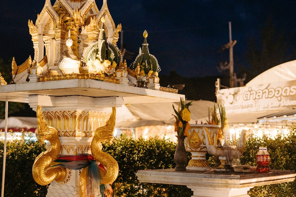 A temple with intricate golden decorations and a large golden spire at night.