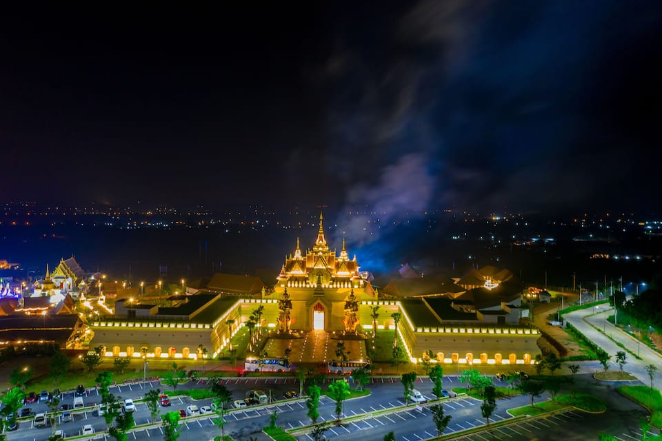 A brightly lit temple complex at night with a large central building and smaller structures around it.