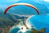 Paragliding in the sky. Paraglider tandem flying over the sea with blue water and mountains in bright sunny day. Aerial view of paraglider and Blue Lagoon in Oludeniz, Turkey. Extreme sport. Landscape