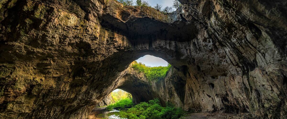 A natural rock arch formation with a path leading through it.