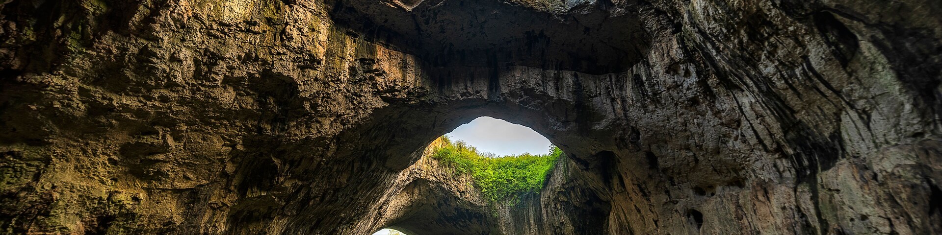 A natural rock arch formation with a path leading through it.