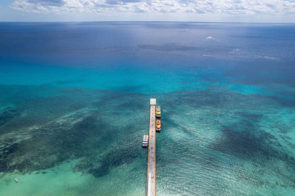 Vista aérea de un puente sobre aguas turquesas y un cielo despejado.