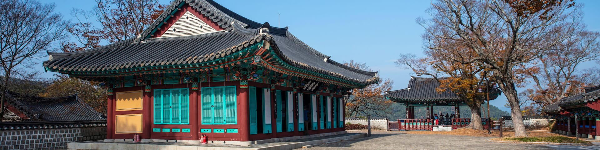 A traditional Korean pavilion with a tiled roof and vibrant green and red walls.