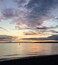 Ein Sonnenuntergang über einem ruhigen Meer mit der Silhouette einer Person, die auf einem Paddleboard steht.
