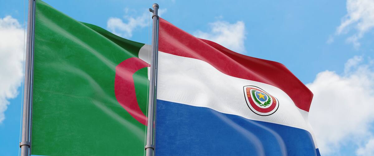 Paraguay and Algeria flags waving in the wind against white cloudy blue sky together. Diplomacy concept, international relations.