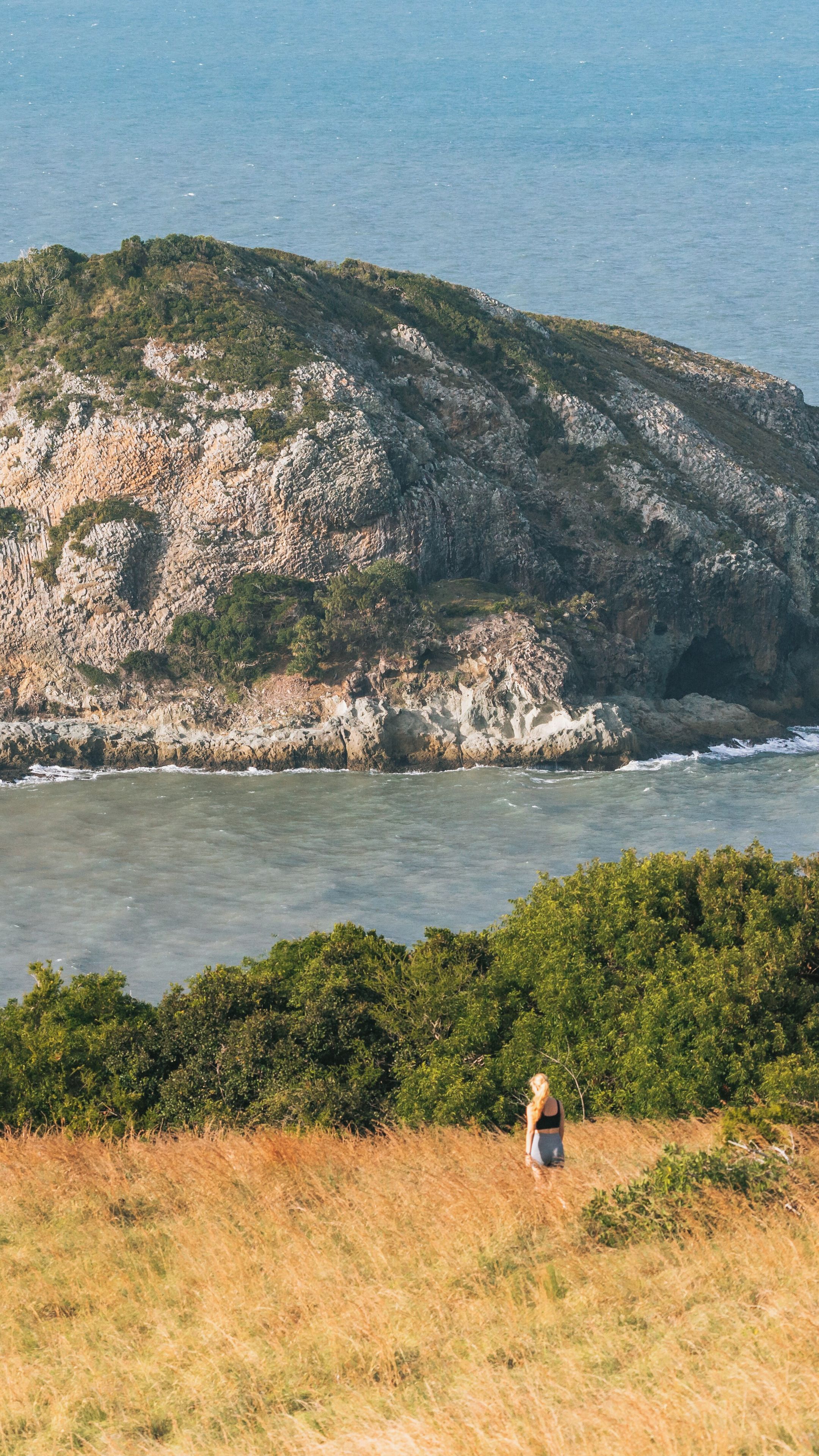 A coastal landscape with rocky cliffs and a person standing in the foreground.