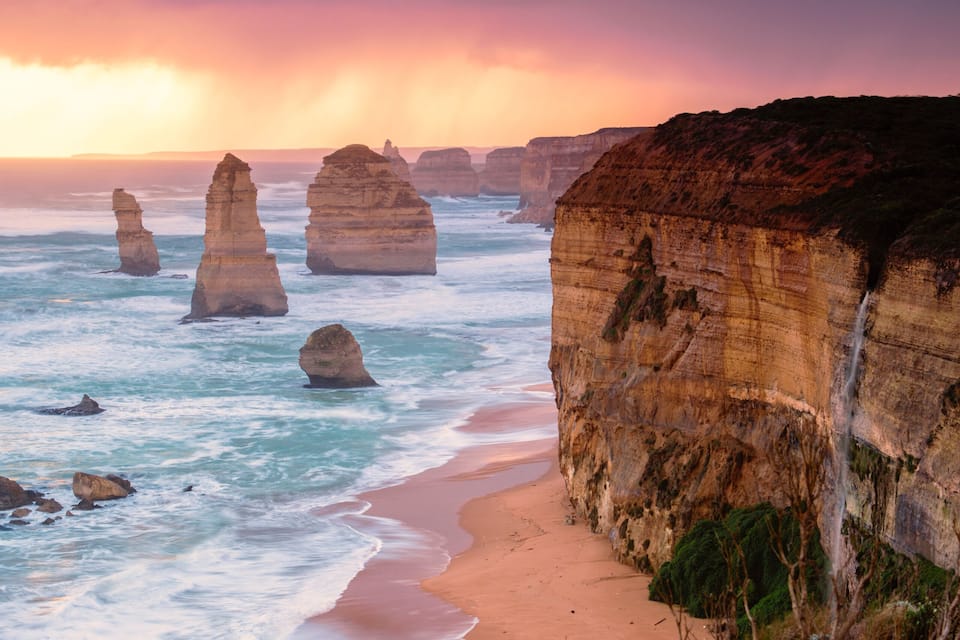 A coastal landscape with prominent rock formations and a sandy beach.