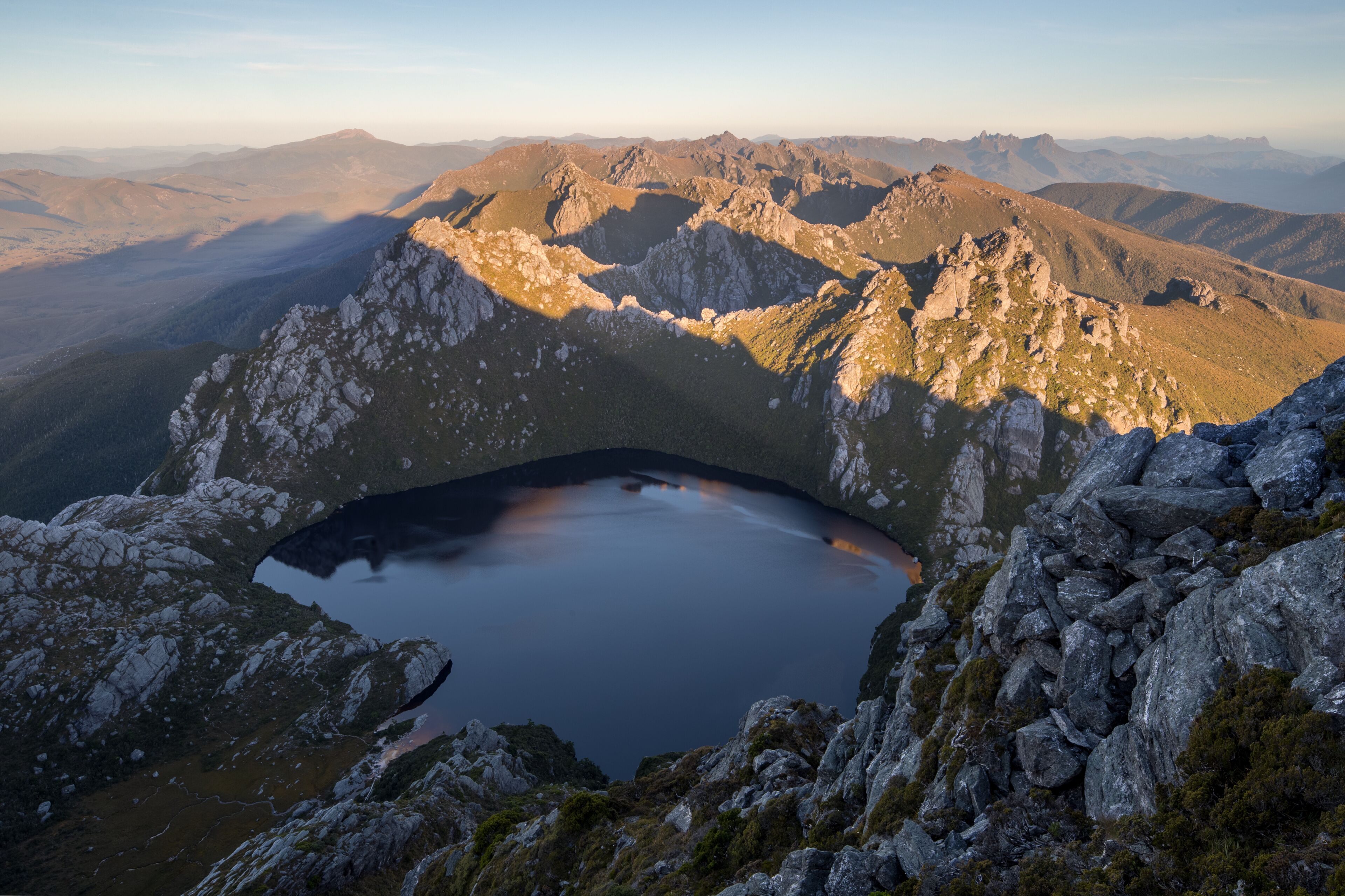 A mountain landscape with a lake nestled in a rocky basin surrounded by rugged peaks.