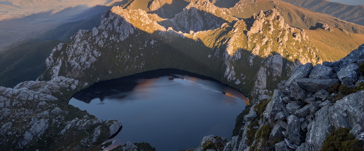 A mountain landscape with a lake nestled in a rocky basin surrounded by rugged peaks.