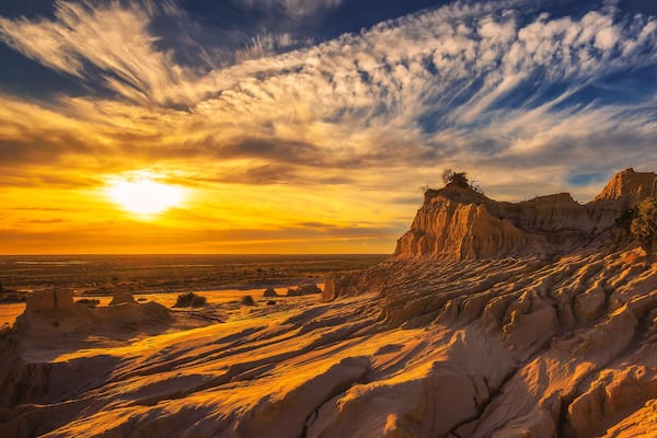 A desert landscape with prominent rock formations and a sunset.