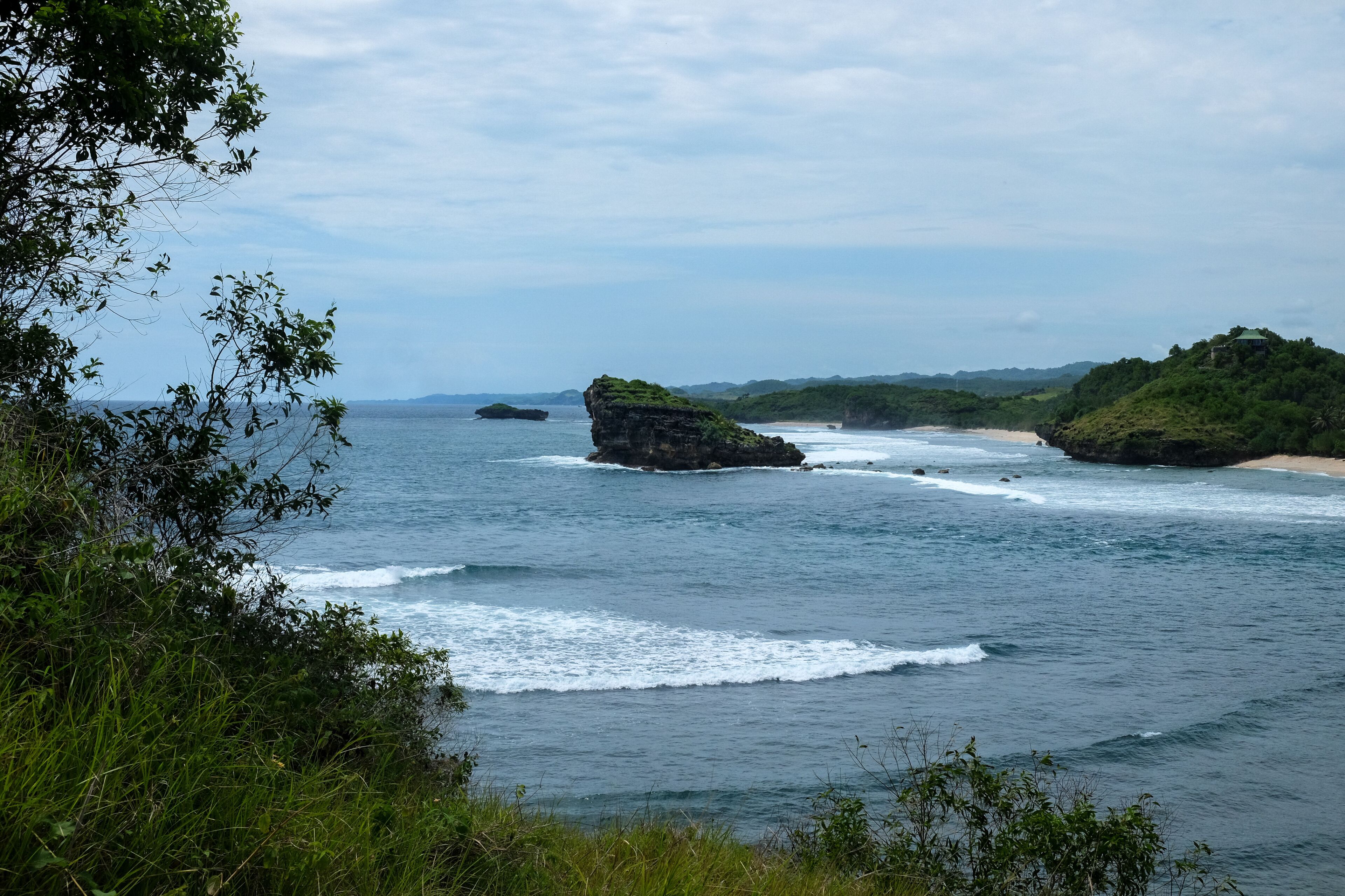 A coastal landscape with rocky outcrops and a beach.